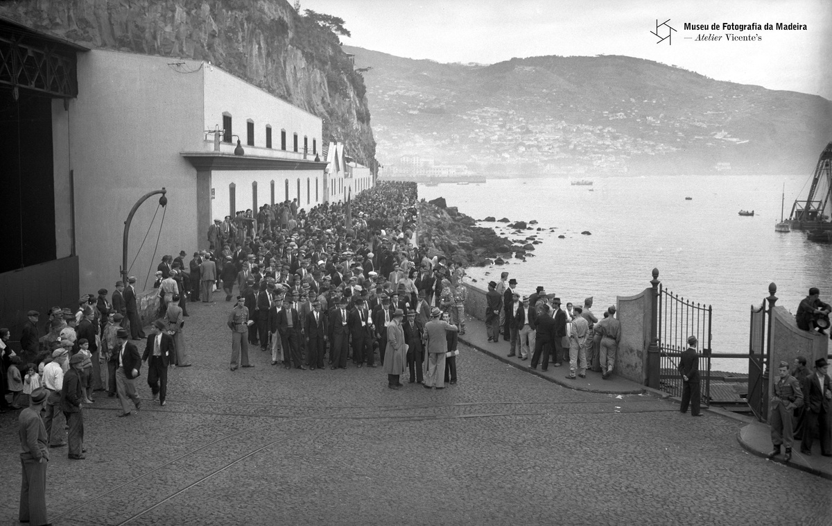FOTO FIGUEIRAS | Emigrantes para o Curaçau na estrada da Pontinha (atual avenida Sá
Carneiro), antes do embarque, Freguesia de São Pedro (atual Freguesia da Sé),
Concelho do Funchal | 1944-03 | 10 x 15 cm | Negativo simples, vidro| Gelatina e
sais de prata | MFM-AV, inv. PHF/1251 | Em depósito na DRABM