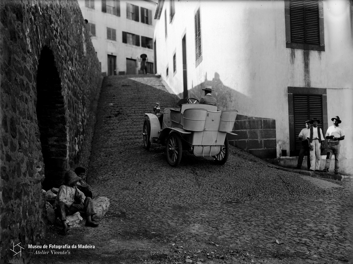 PHOTOGRAPHIA VICENTE | Harvey Foster conduzindo o seu
automóvel na rampa da Pontinha (atual rampa do Carvão), freguesia de São Pedro
(atual Freguesia da Sé), concelho do Funchal | 1904-05-17 | 17,8 X 23,8 cm | Negativo simples, vidro | Gelatina
e sais de prata | MFM-AV, inv. VIC/5189 | Em depósito na DRABM