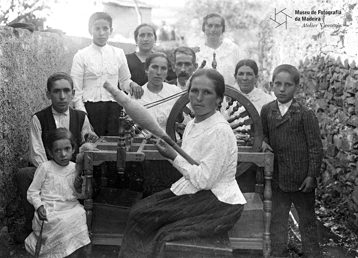 FRANCISCO JOÃO BARRETO - Retrato de grupo junto a uma roda de fiar, freguesia da Fajã da Ovelha, concelho da Calheta | 1925 - 8,9 x 11,8 cm - Negativo simples, vidro - Gelatina sais de prata - MFM-AV, Inv. FJB/13 - Em depósito no ABM