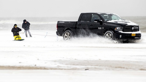 Dois jovens fazem ‘snowboard’ à boleia de uma carrinha em Egmond aan Zee, Holanda. FOTO KOEN VAN WEEL/EPA