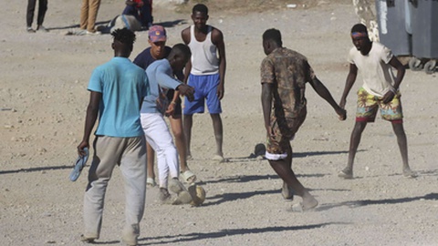 Alguns dos 2.500 jovens migrantes que chegaram a Ceuta há alguns dias e que continuam no exclave espanhol, jogam futebol na Praia do Trampolim.&nbsp; Foto&nbsp;REDUAN/EFE/EPA