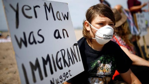 Uma jovem em protesto com um cartaz a dizer: “A sua mãe foi uma emigrante”. Foto REUTERS/Henry Nicholls