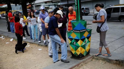 Populares em torno de um posto de carregamento de telemóveis alimentado a energia solar. Foto Carlos Garcia Rawlins/Reuters