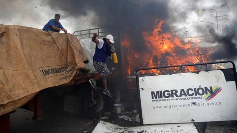 Manifestante tenta apagar incêndio com um extintor.  Foto REUTERS/Marco Bello