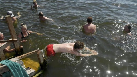 As pessoas foram a banhos em águas que, mesmo no verão, são normalmente frias.   Foto Markku Ulander/Lehtikuvavia 