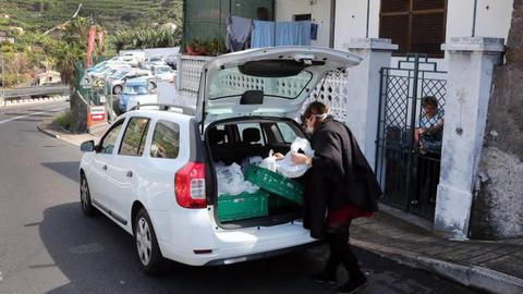 Elementos da equipa mobilizada pela junta de freguesia de São Martinho distribuem refeições a um dos cerca de 40 agregados familiares carenciados, um trabalho que decorre de segunda a sexta-feira. Fotos Homem de Gouveia/Lusa
